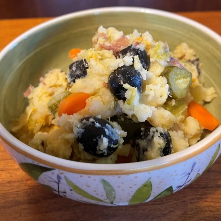 Bowl of mashed potatoes with olives and other veggies